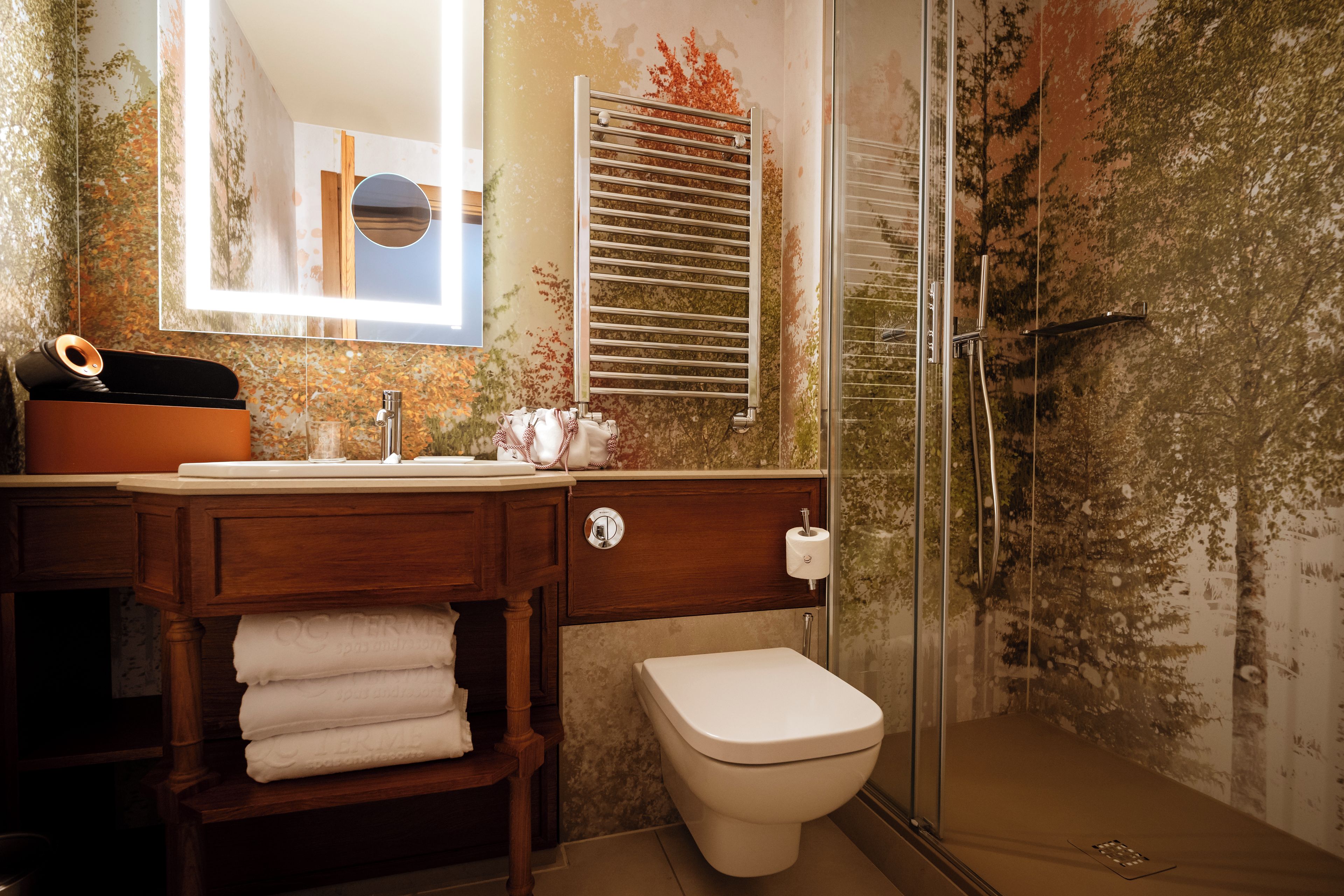 Un baño con tocador de madera, inodoro y zona de ducha.