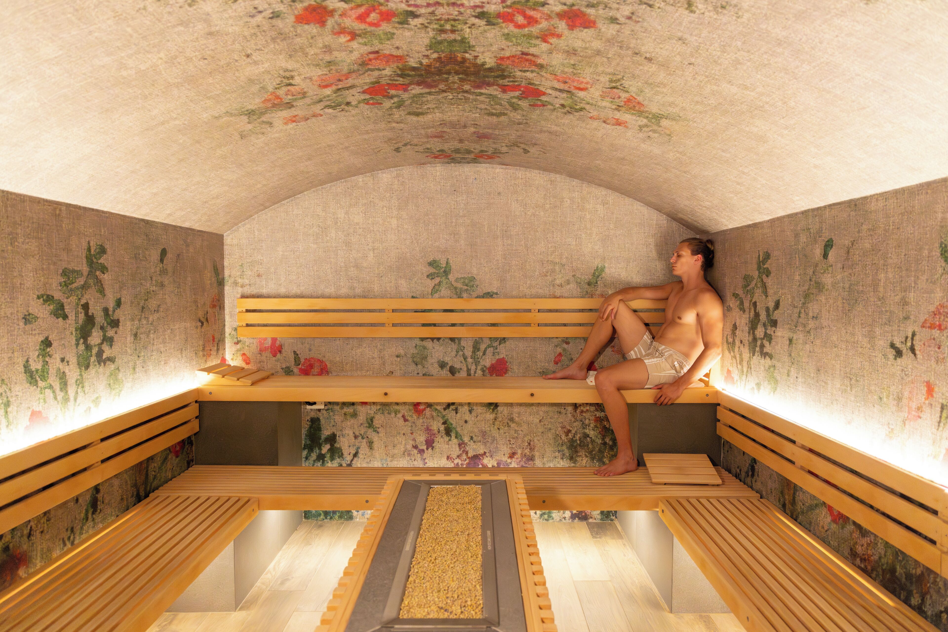 Una sauna con bancos de madera y un diseño floral en el techo.