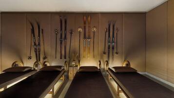 A room with four wooden benches, a wall-mounted ski rack, and a small table with a lamp.