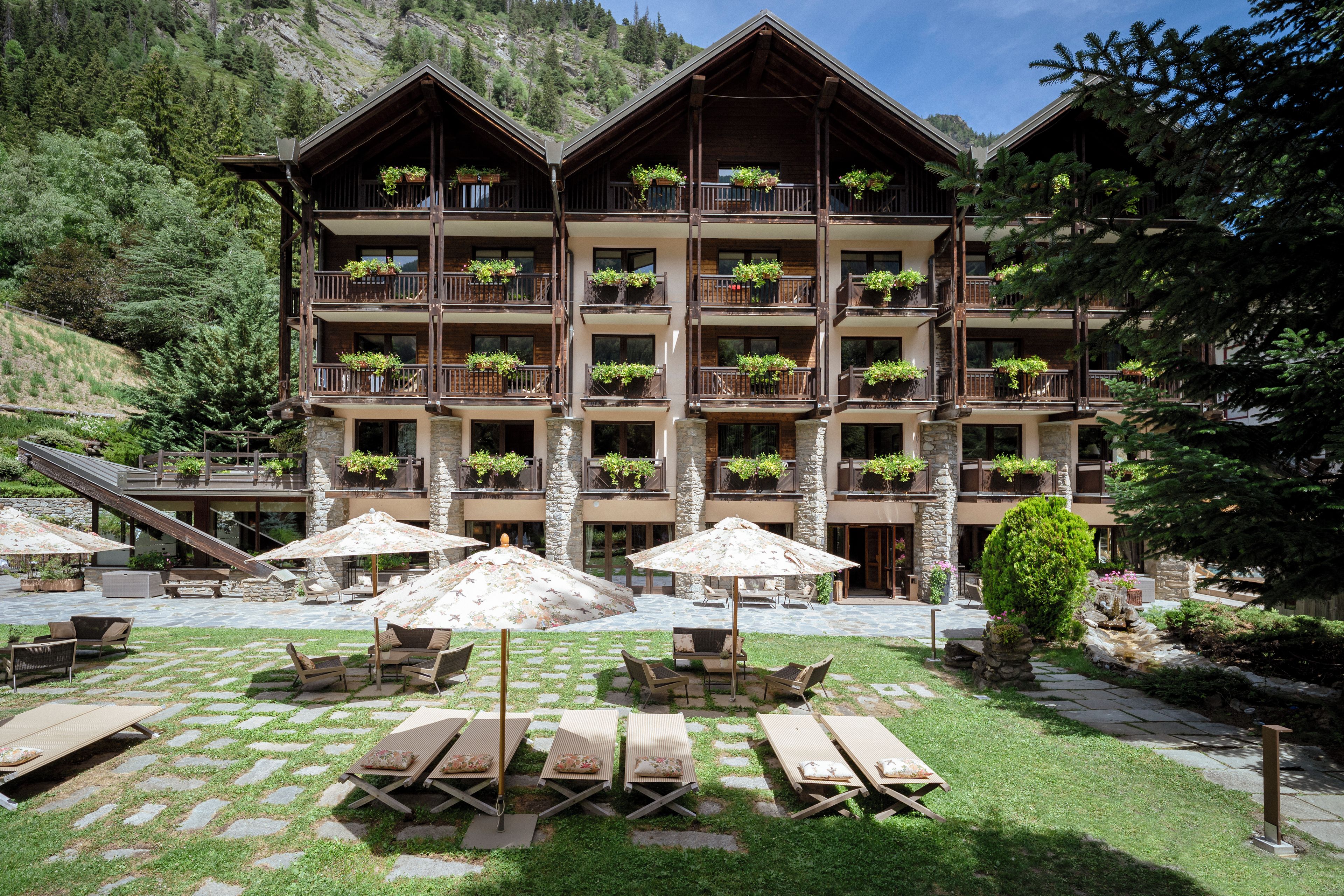 Un hôtel à plusieurs étages doté de balcons, d’un espace extérieur aménagé et surplombant un paysage montagneux.