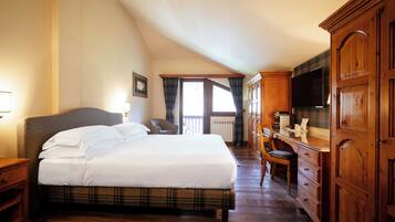 A hotel room with a large bed, wooden wardrobe, and a television.