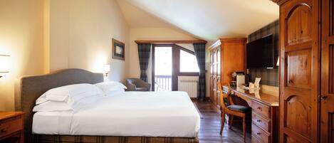 A hotel room with a large bed, wooden wardrobe, and a television.