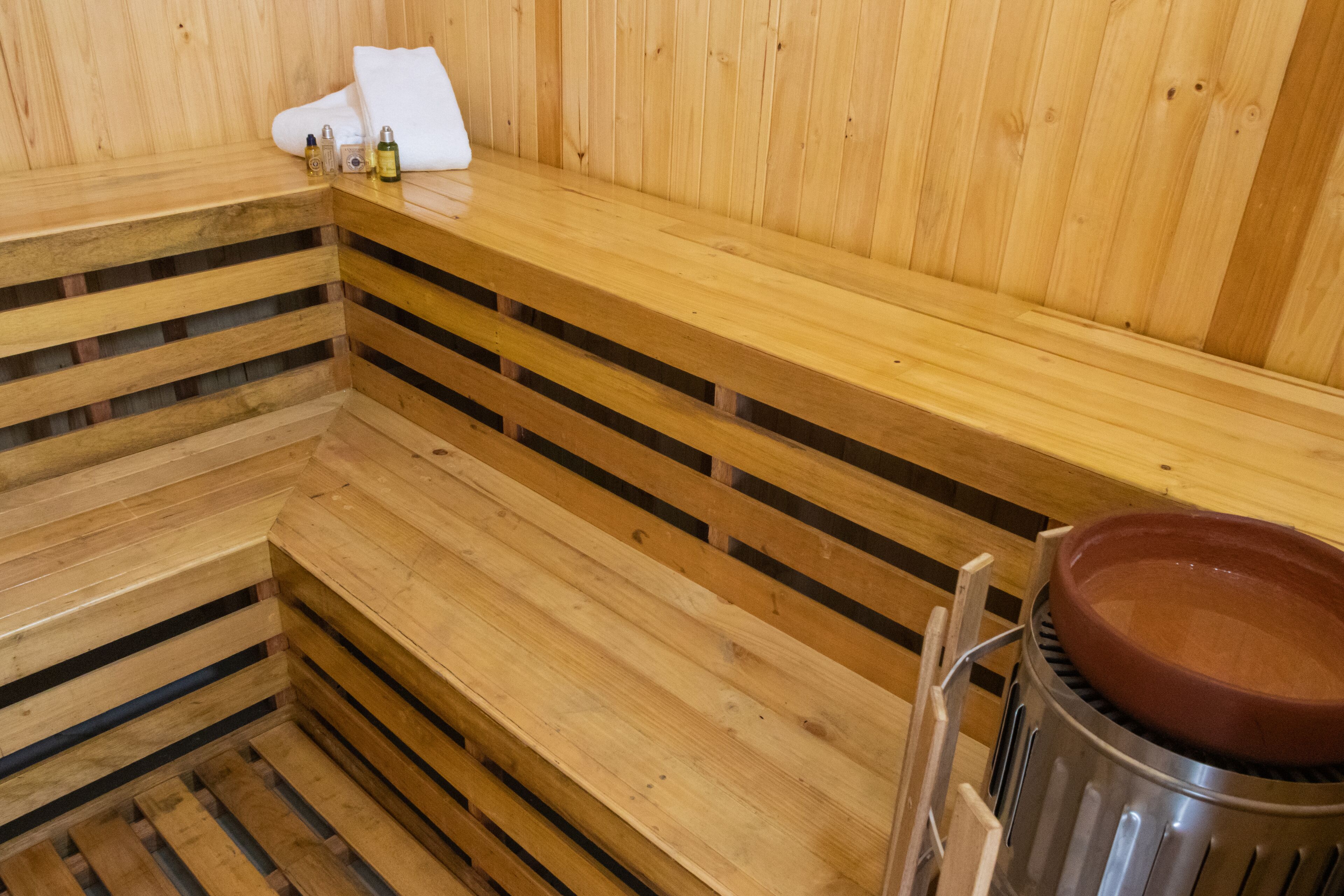 Een houten sauna bank met een handdoek en flessen erop.