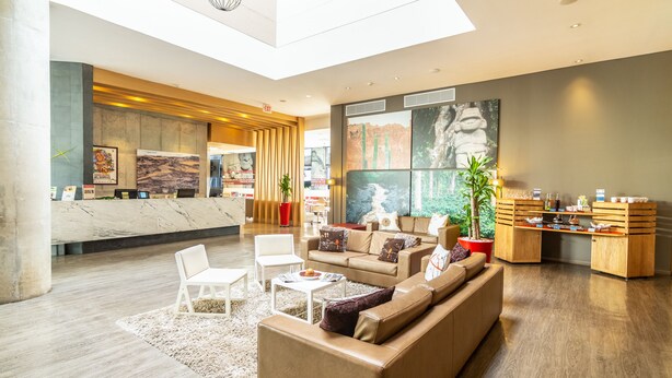 A spacious lobby with a reception desk, seating area, and artwork on the walls. - GHL Hotel Neiva (Neiva)