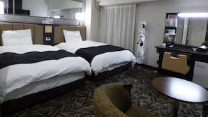 Una habitación de hotel con dos camas, un escritorio, una silla y una pequeña mesa.