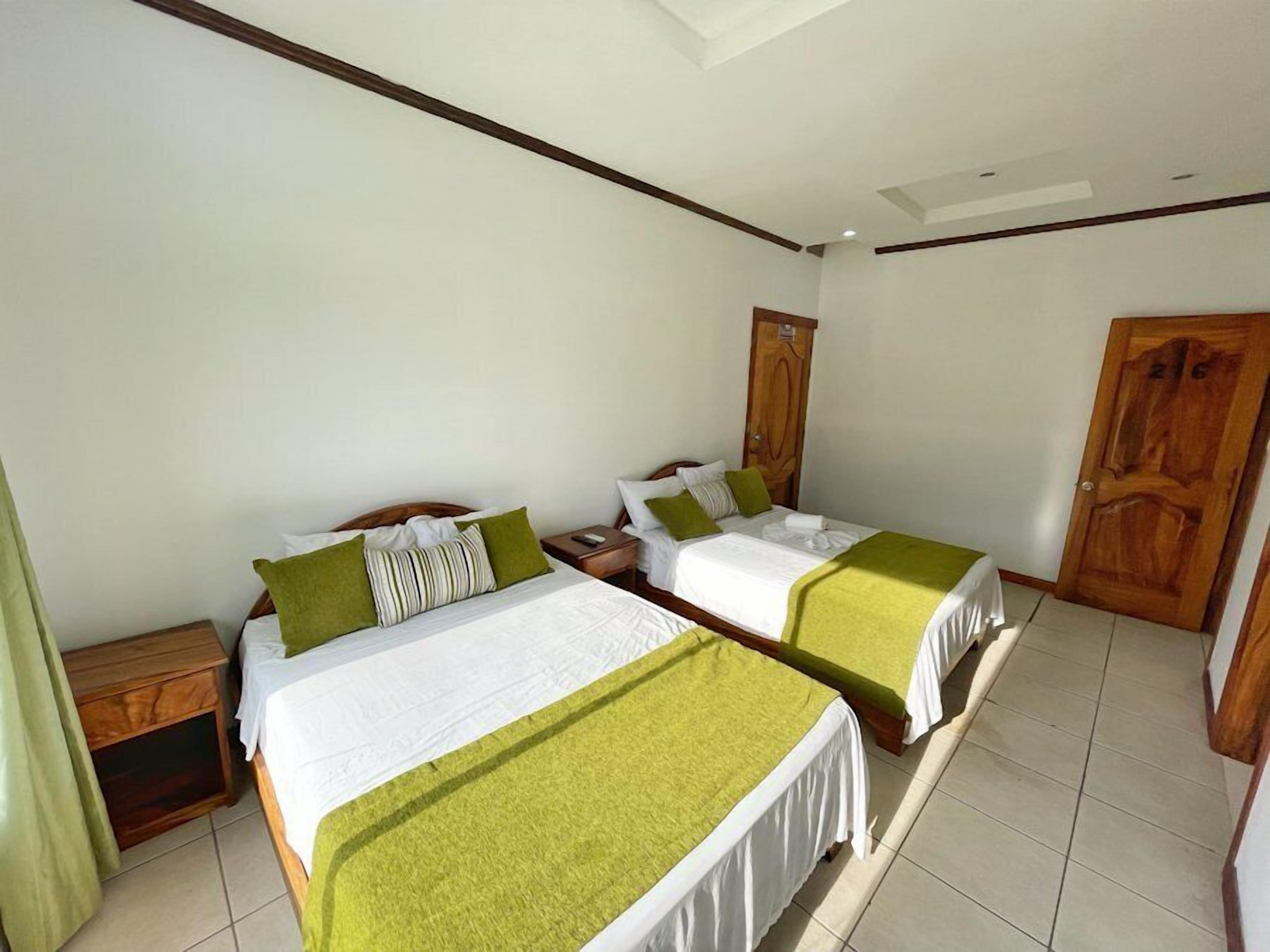 Een kamer met twee bedden, houten hoofdborden, een nachtkastje en een deur.