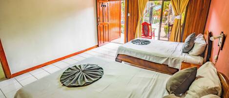 A room with two beds, a wooden ceiling, and a sliding door leading to an outdoor area.