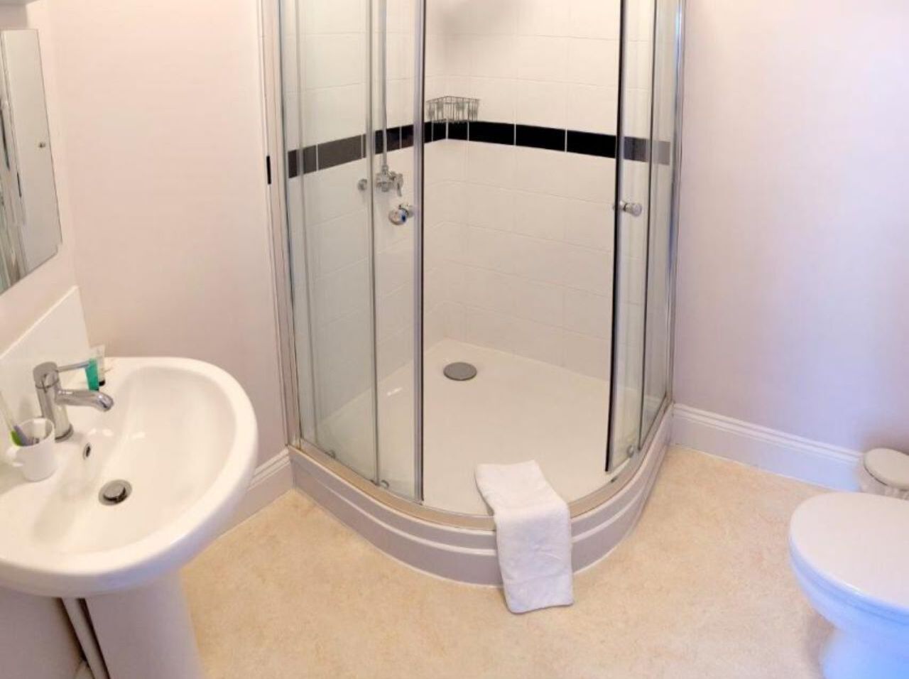 A bathroom with a glass-enclosed shower, a sink, and a toilet.