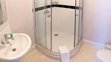 A bathroom with a glass-enclosed shower, a sink, and a toilet.