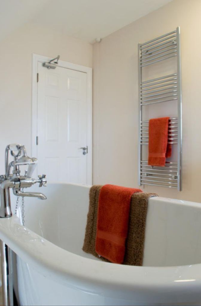 A bathroom with a white bathtub, a white door, and a towel rack with a towel.
