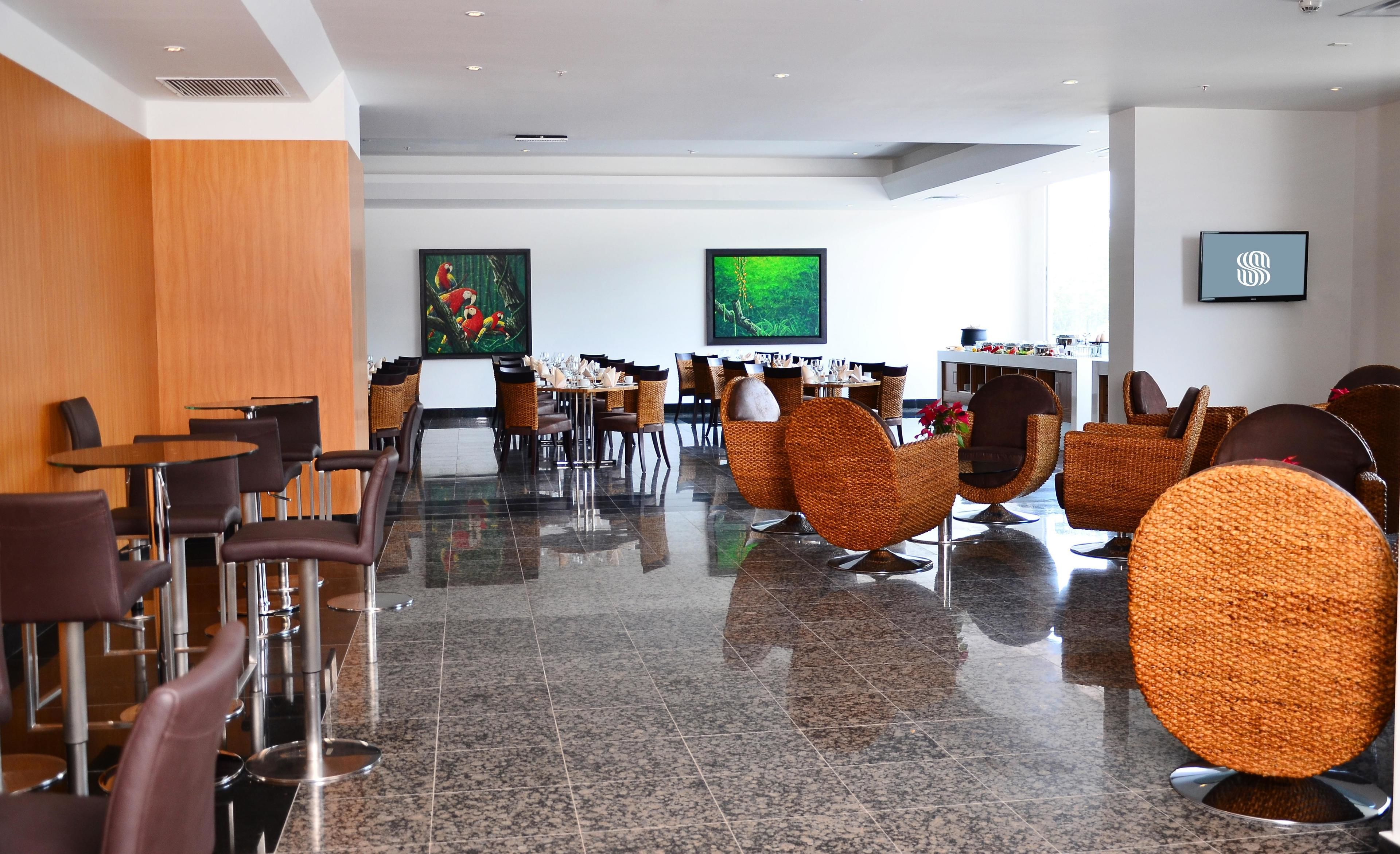 A modern hotel lobby with a polished granite floor, wicker chairs, and a reception desk.