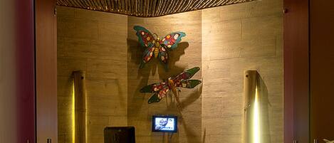 Zona de recepción con un cartel que dice "Wet & Green Spa" y una mariposa decorativa en la pared.