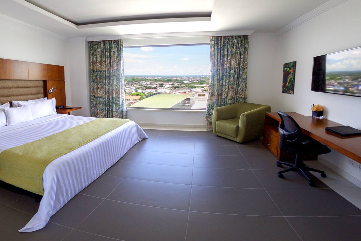 Une chambre d’hôtel avec un grand lit, un bureau, une chaise et une vue sur la ville.