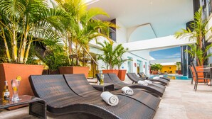Un espace aménagé au bord de la piscine, avec des chaises longues, une piscine et des plantes en pot.