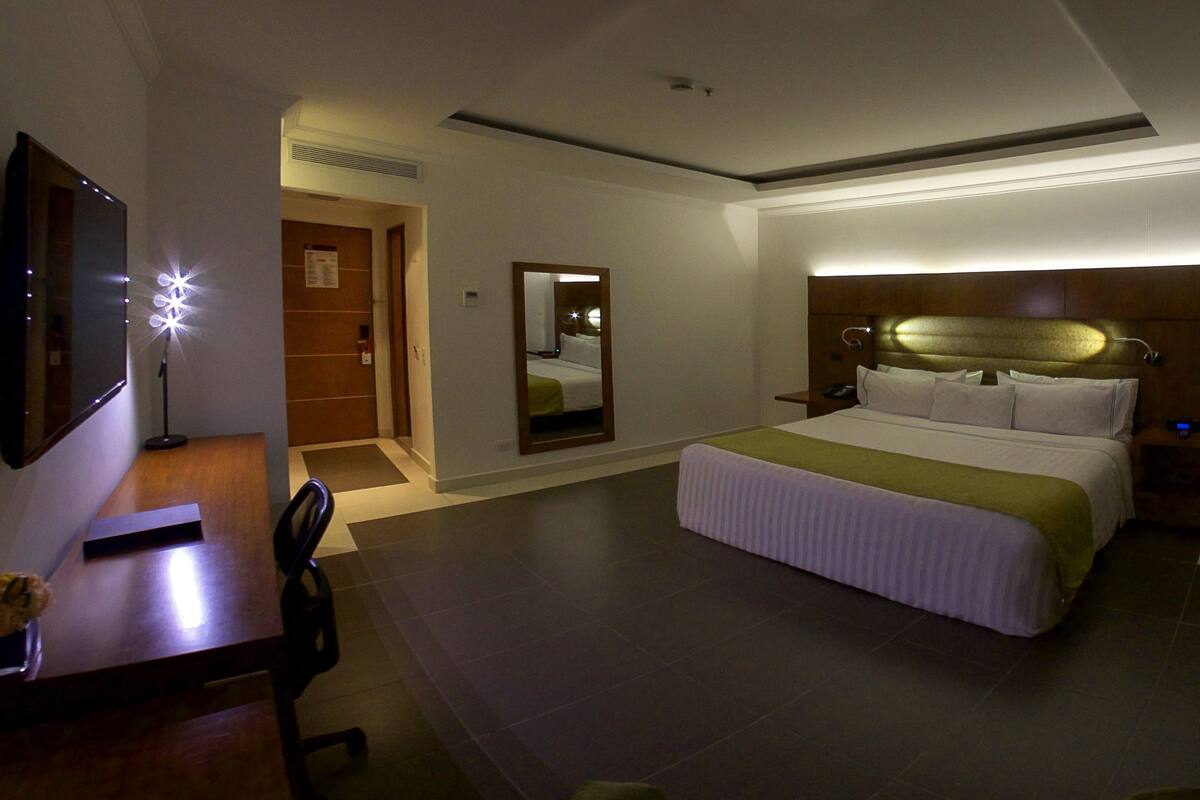 Une chambre d’hôtel comprenant un lit, une table de chevet, une chaise, un bureau et un miroir.