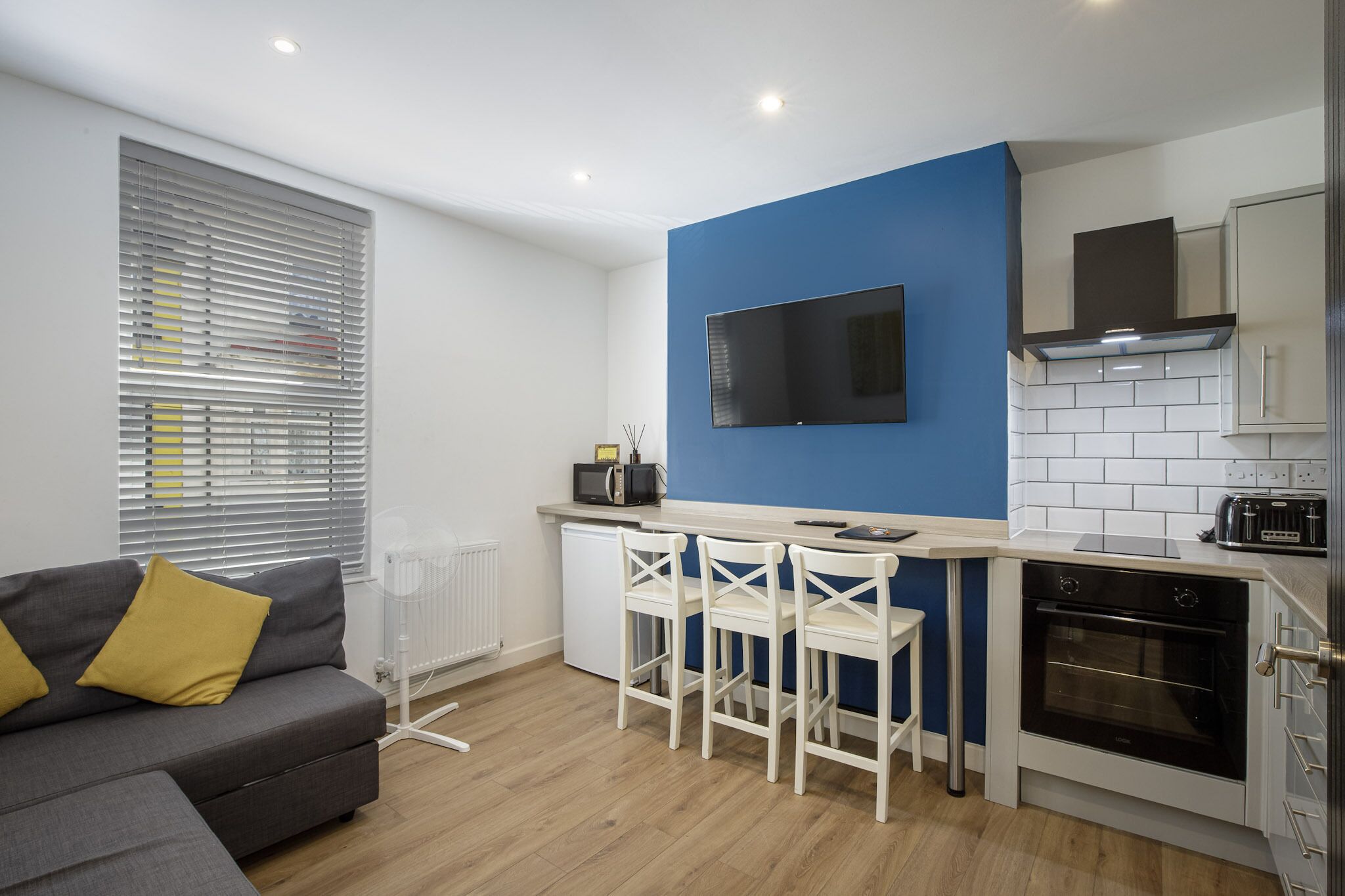 A modern kitchen with a blue accent wall, a built-in oven, and a microwave.