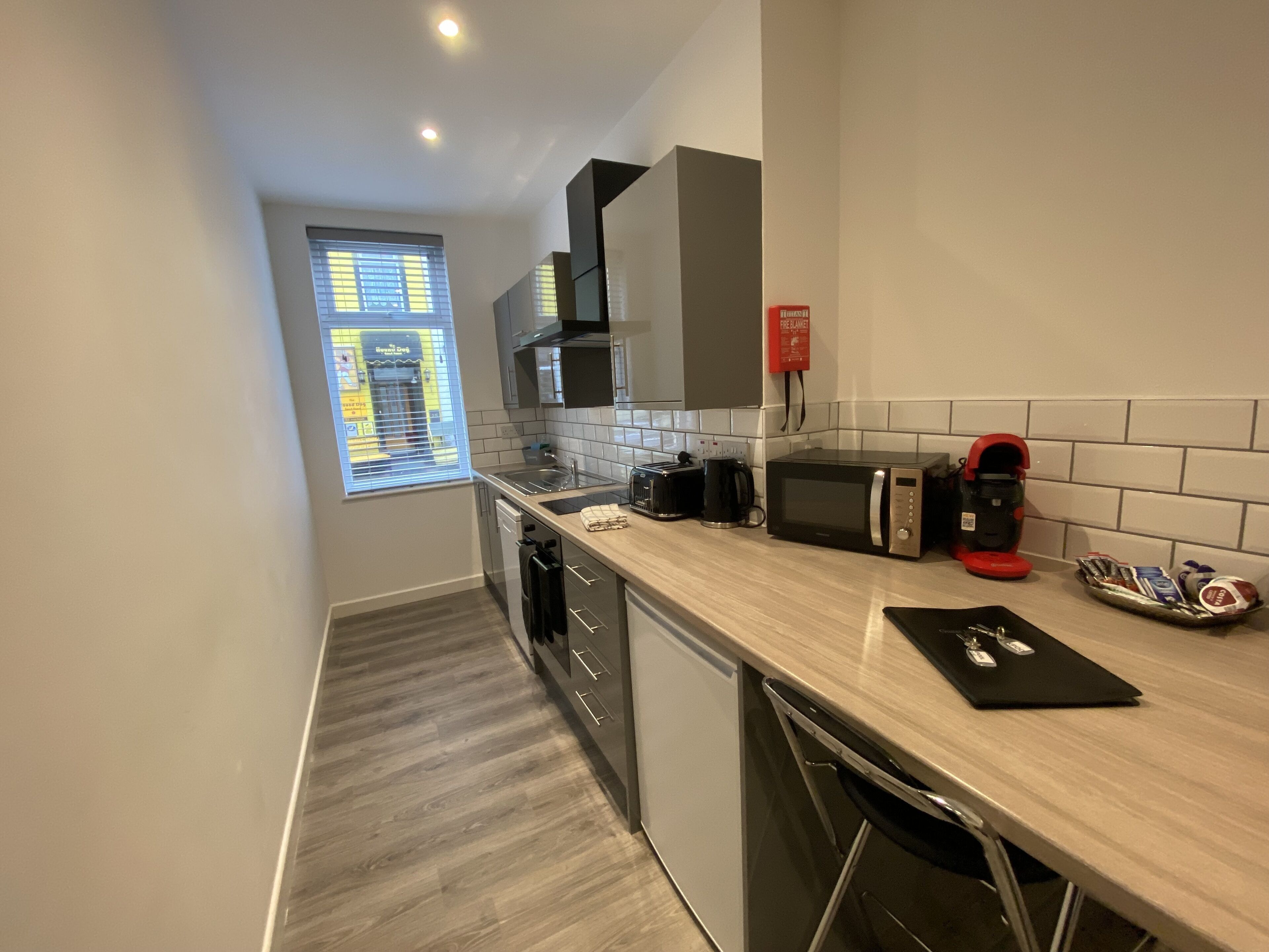 A modern kitchen with a dishwasher, microwave, coffee maker, and a small sink.