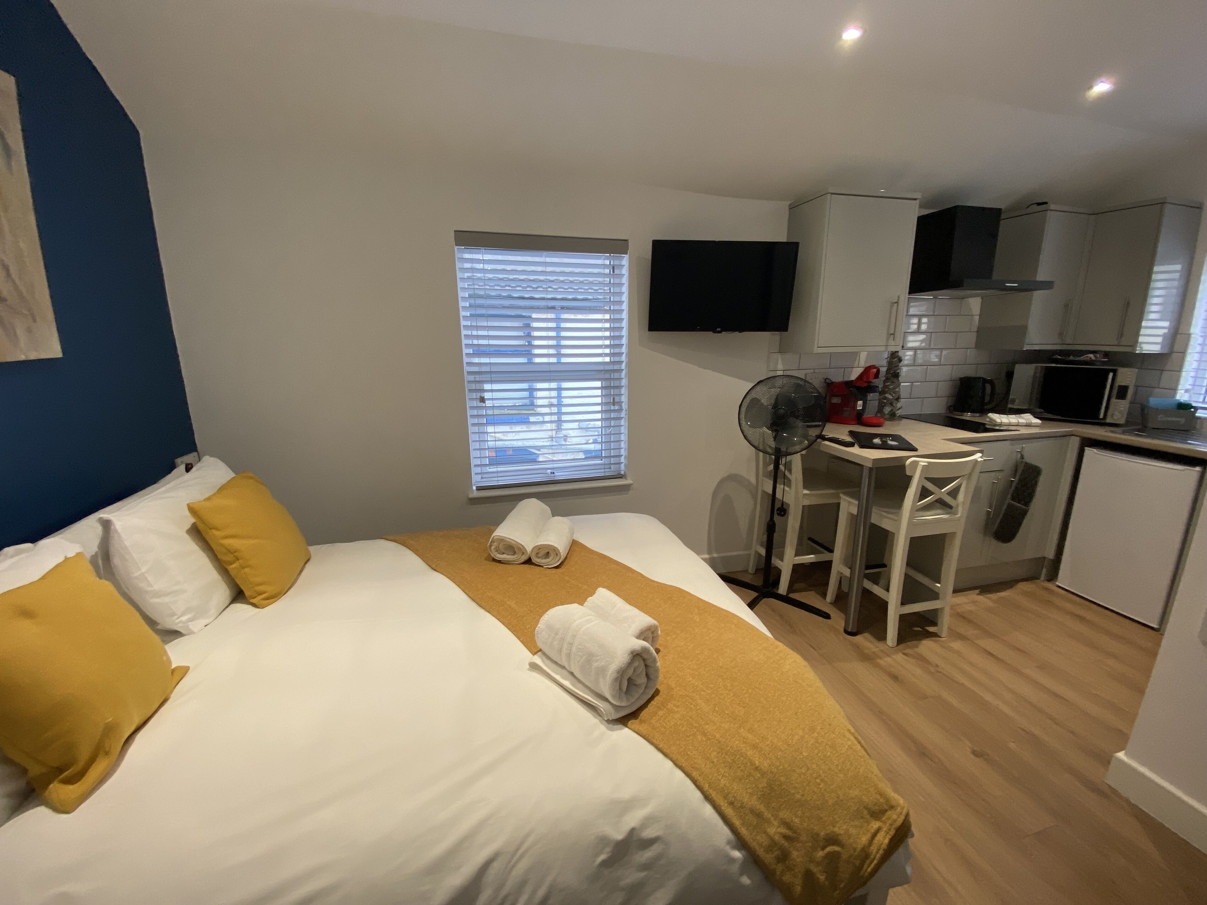 A hotel room with a bed, a desk, a chair, a microwave, and a television.
