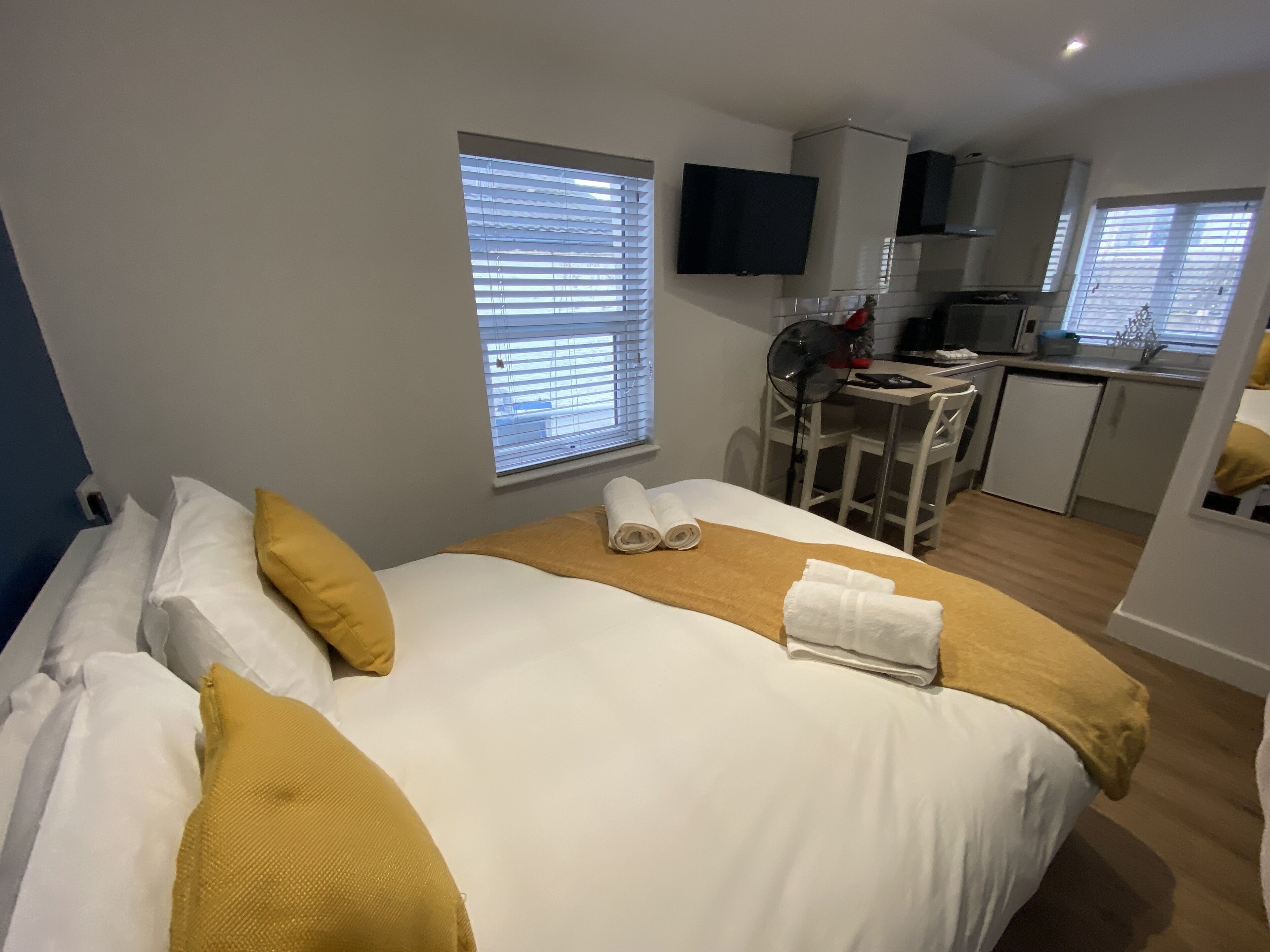 A hotel room with a bed, a desk, and a kitchenette.