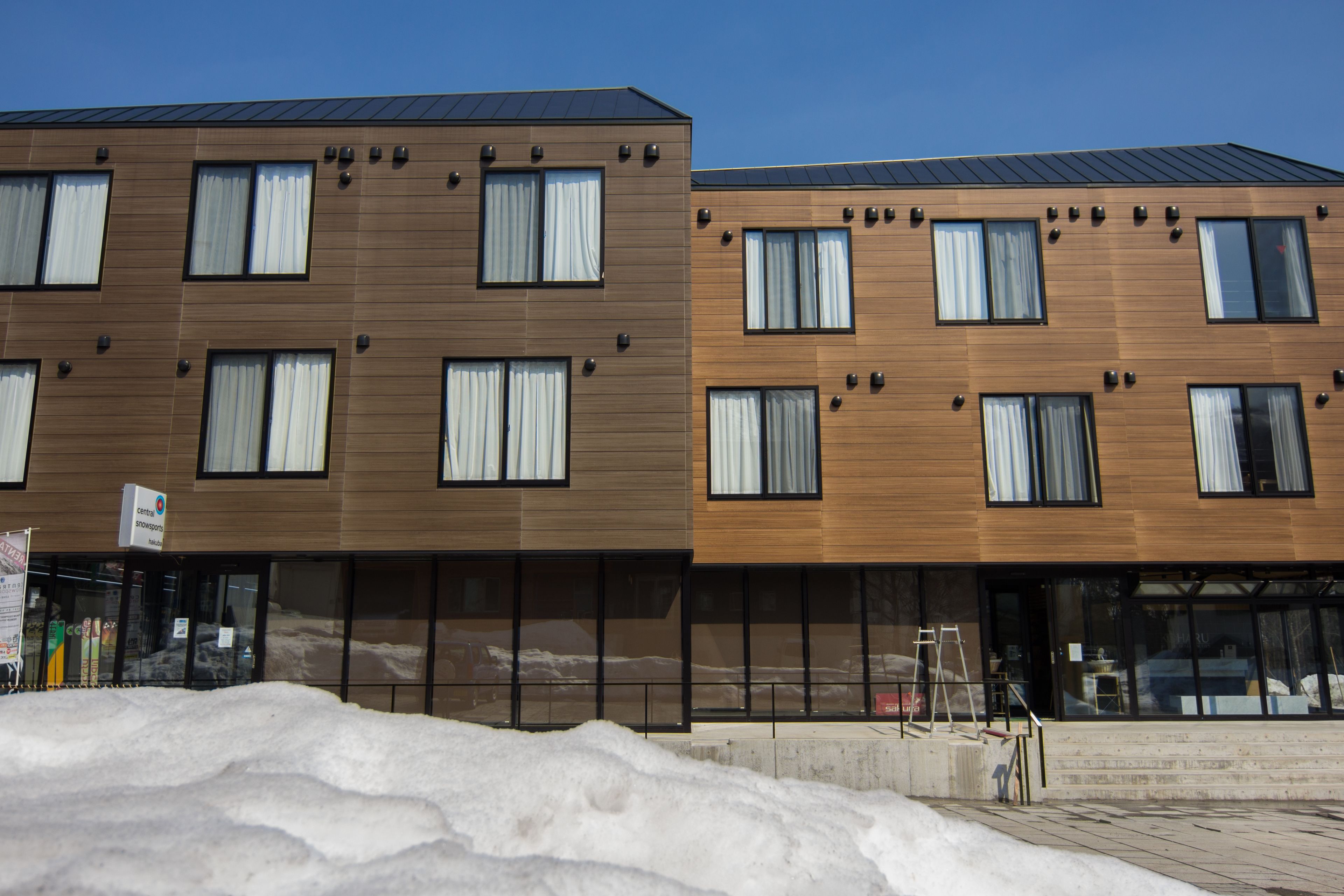 A modern building with multiple windows and a snow-covered ground.