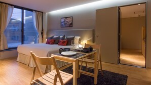 A hotel room with a bed, a dining table with chairs, a small kitchen area, and a large window with curtains. - Koharu Resort Hotel & Suites (Hakuba)
