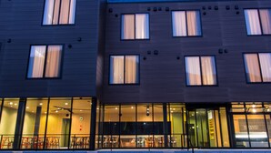 A modern building with multiple windows and a visible entrance area with seating. - Koharu Resort Hotel & Suites (Hakuba)
