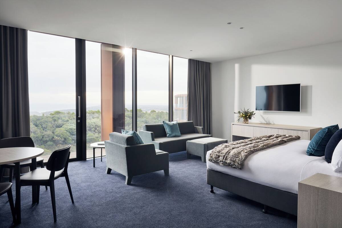 Una habitación de hotel moderna con una cama grande, un sofá, una mesa de comedor y un televisor.