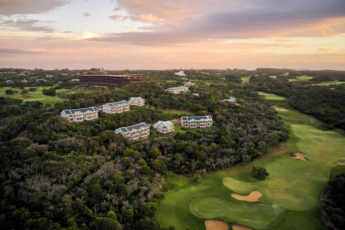 Vista aérea de un campo de golf con varios edificios, rodeado de vegetación densa.