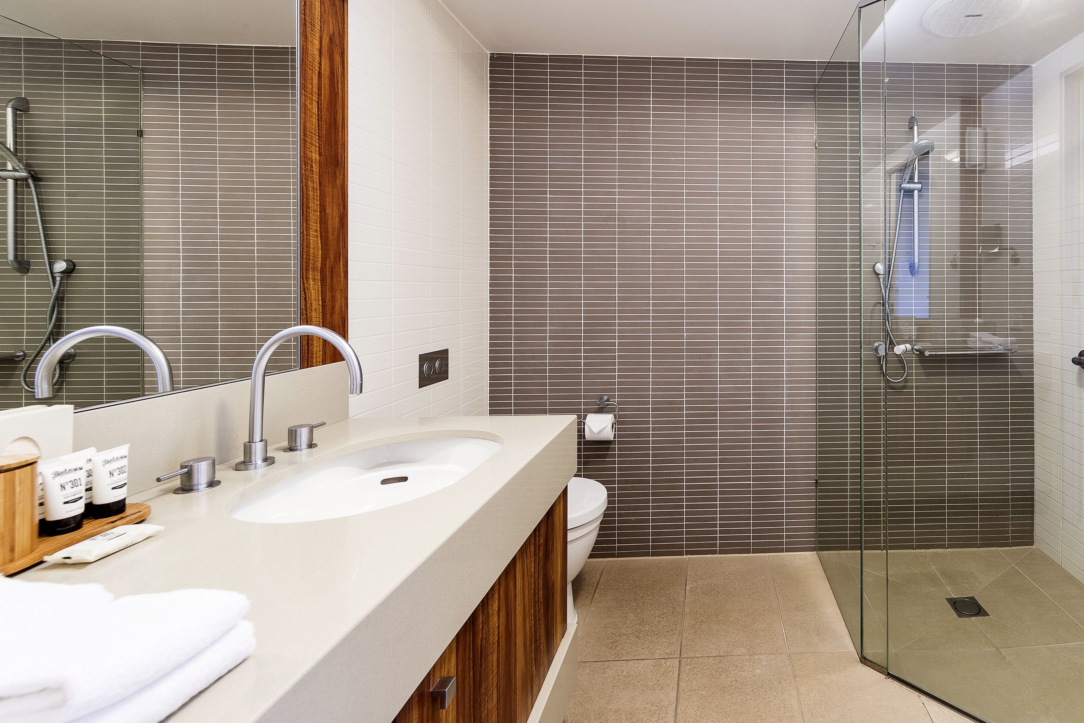 A modern bathroom with a large sink, mirror, and shower area.