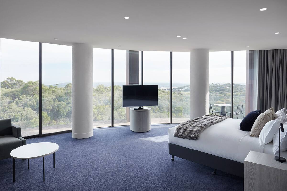 Una habitación de hotel moderna con una cama grande, un televisor de pantalla plana, un sofá y una mesita.