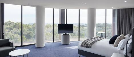 A modern hotel room with a large bed, a flat-screen TV, a sofa, and a small table.