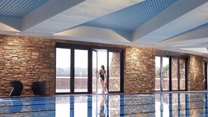 Ein moderner Poolbereich im Innenbereich mit Steinwänden und großen Fenstern.