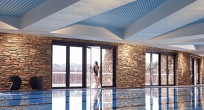 Una piscina techada, una piscina al aire libre, sombrillas