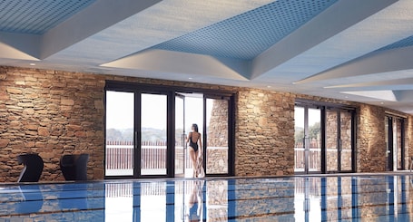 Una piscina techada, una piscina al aire libre, sombrillas