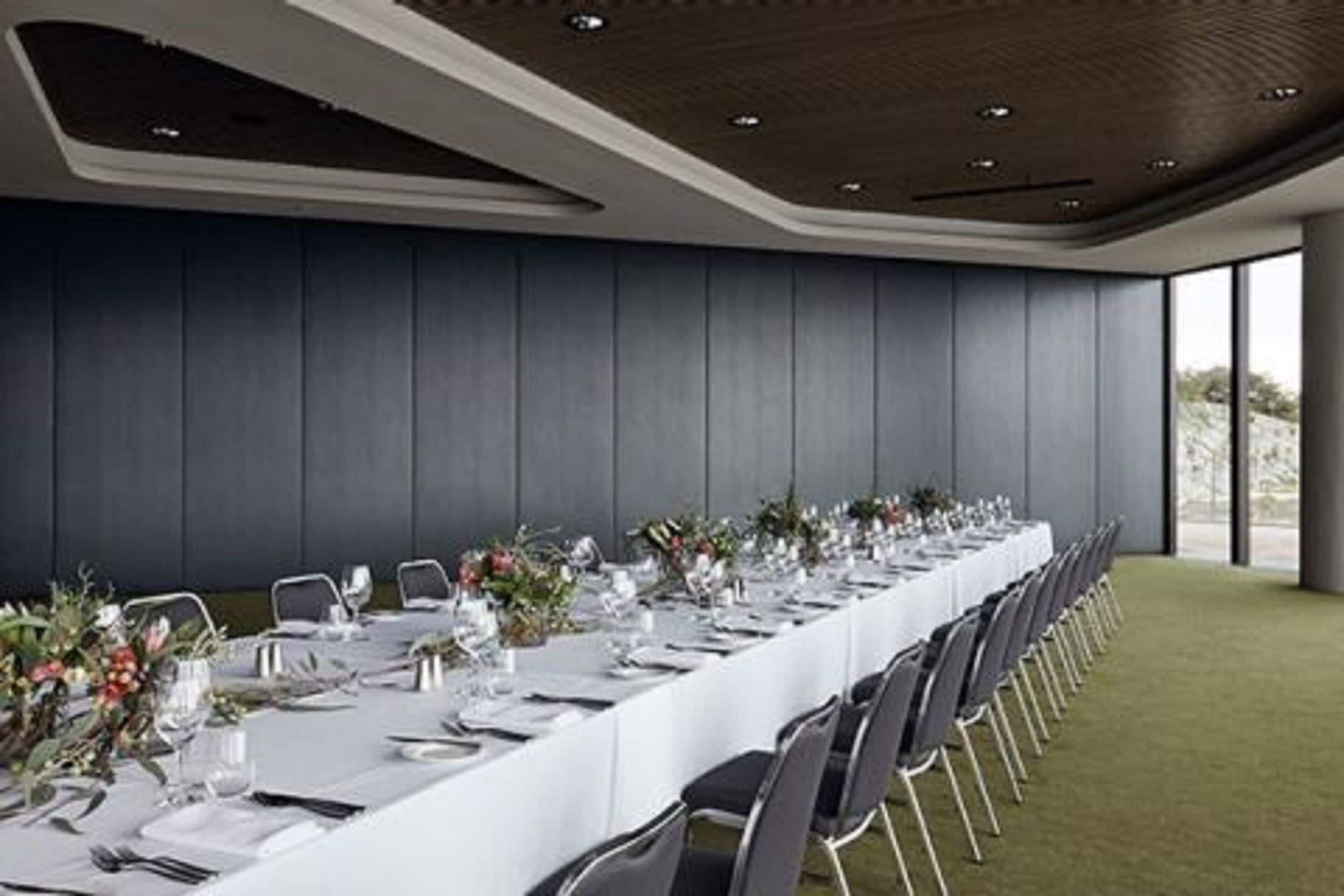 A long dining table set for a formal event, with chairs aligned on both sides.