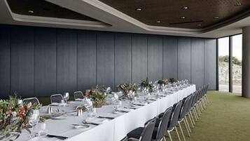 A long dining table set for a formal event, with chairs aligned on both sides.