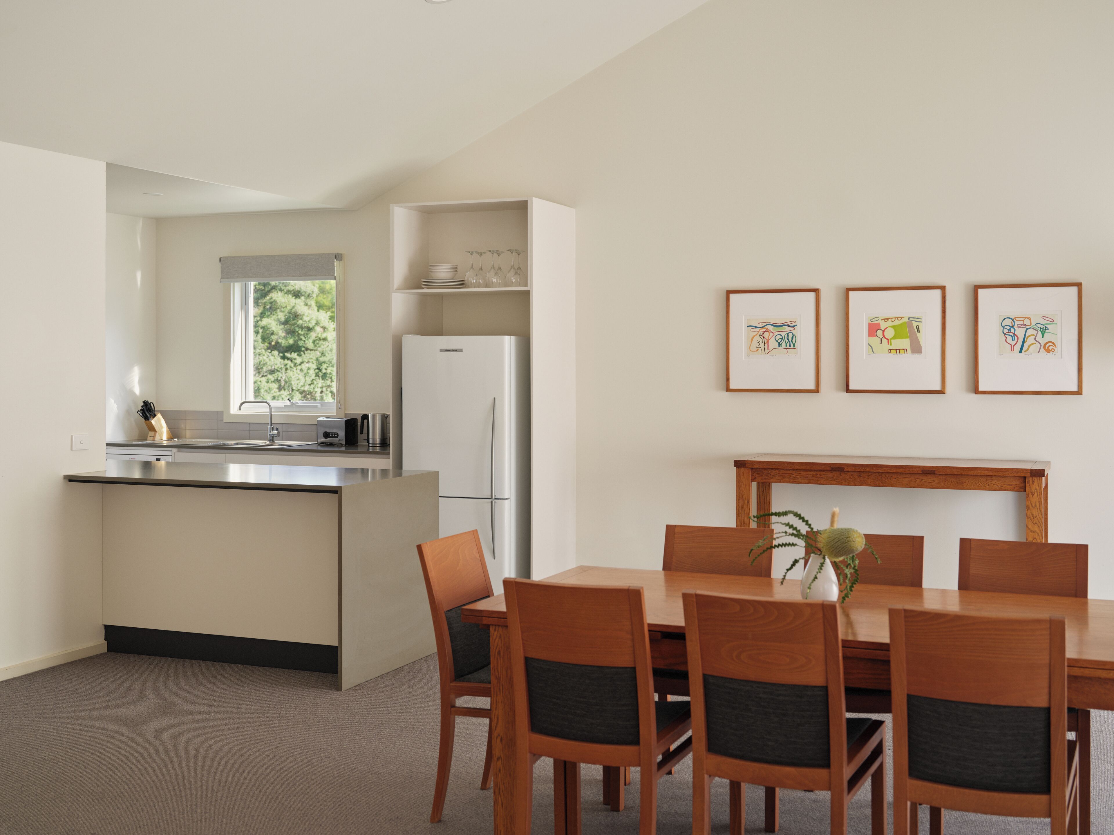 A modern kitchen with a built-in island, stainless steel appliances, and a dining area with wooden furniture.
