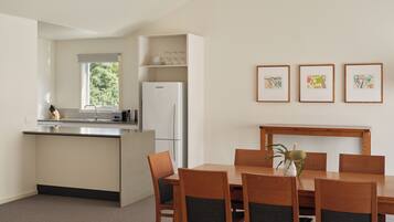 A modern kitchen with a built-in island, stainless steel appliances, and a dining area with wooden furniture.