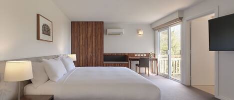 A hotel room with a large bed, a desk, a chair, a TV, and a balcony.