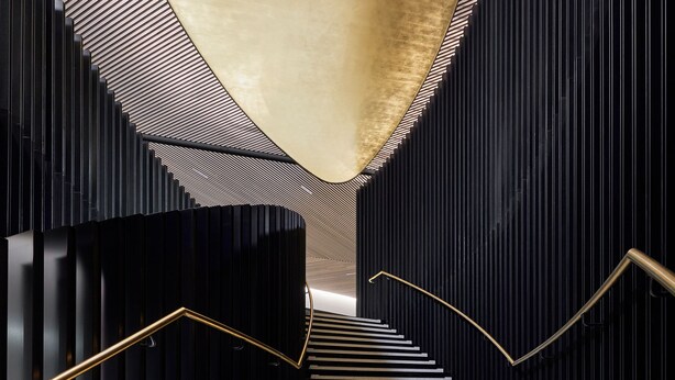 Eine moderne Treppe mit schwarz-weißen Stufen, einem geschwungenen Geländer und einer strukturierten Decke.