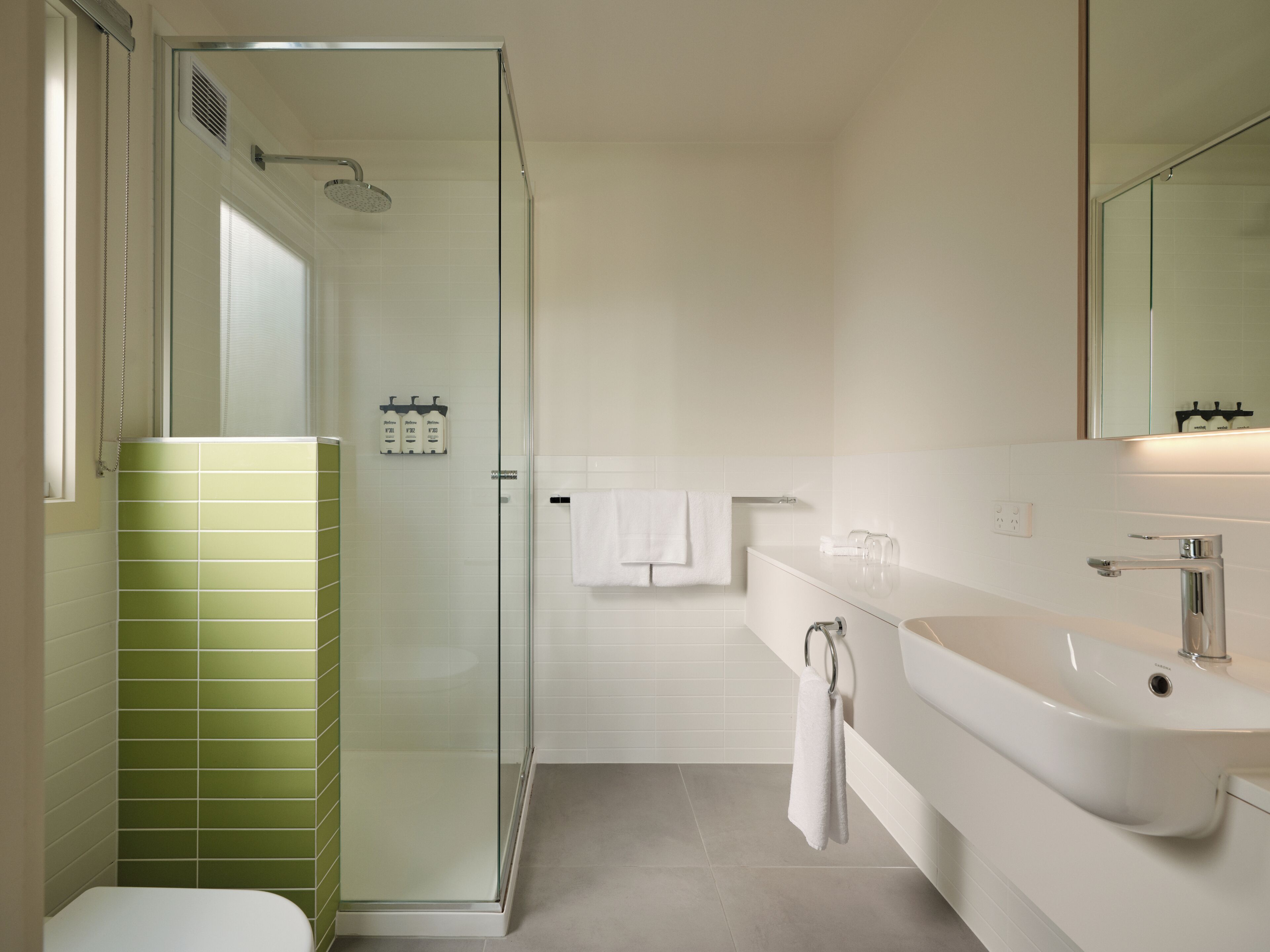 A modern bathroom with a glass-enclosed shower, a white sink, and a toilet.