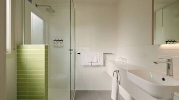 A modern bathroom with a glass-enclosed shower, a white sink, and a toilet.