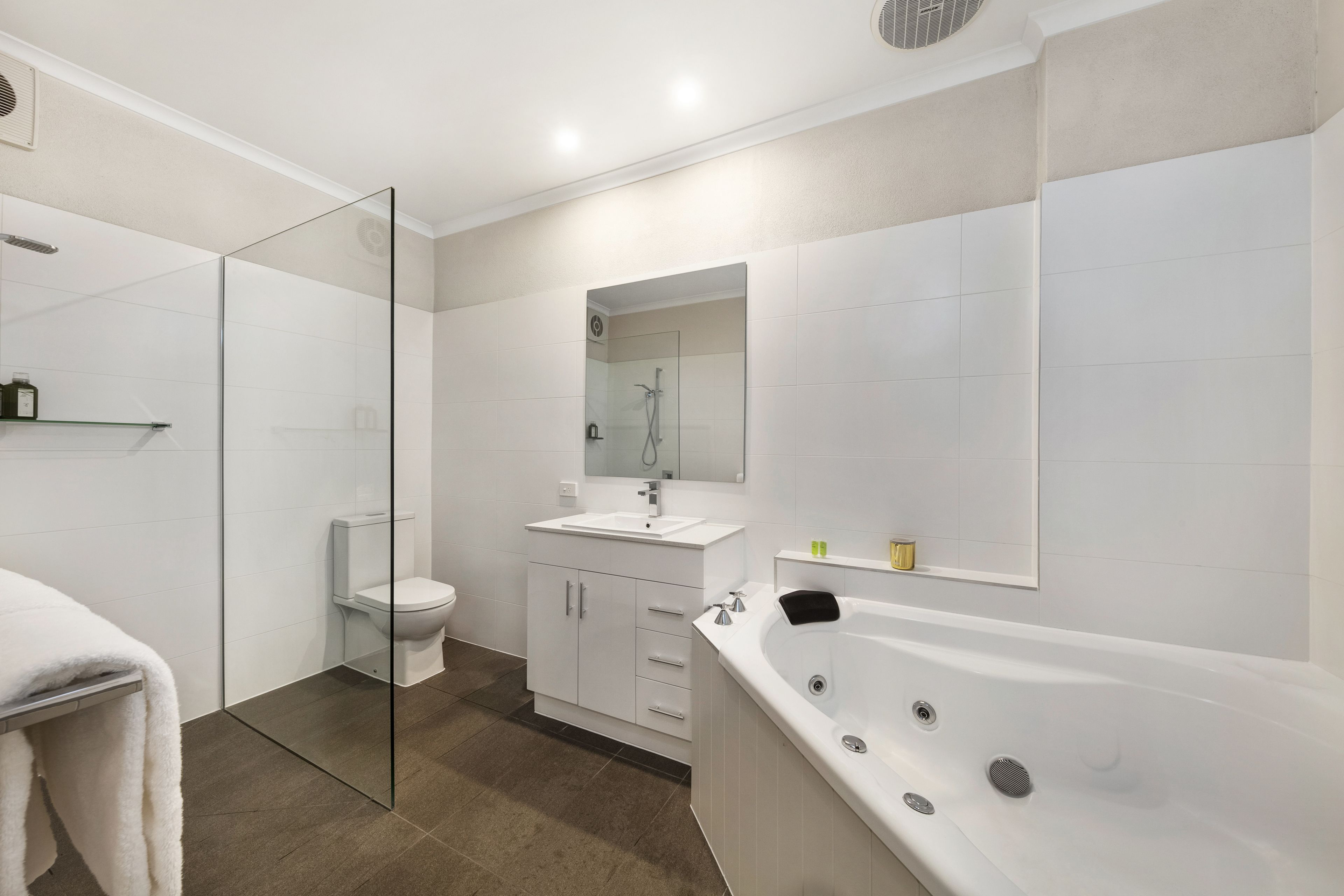 Een moderne badkamer met een glazen douchecabine, een witte wastafel, een toilet en een vrijstaand bad.
