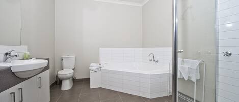 A modern bathroom with a shower, toilet, and sink.