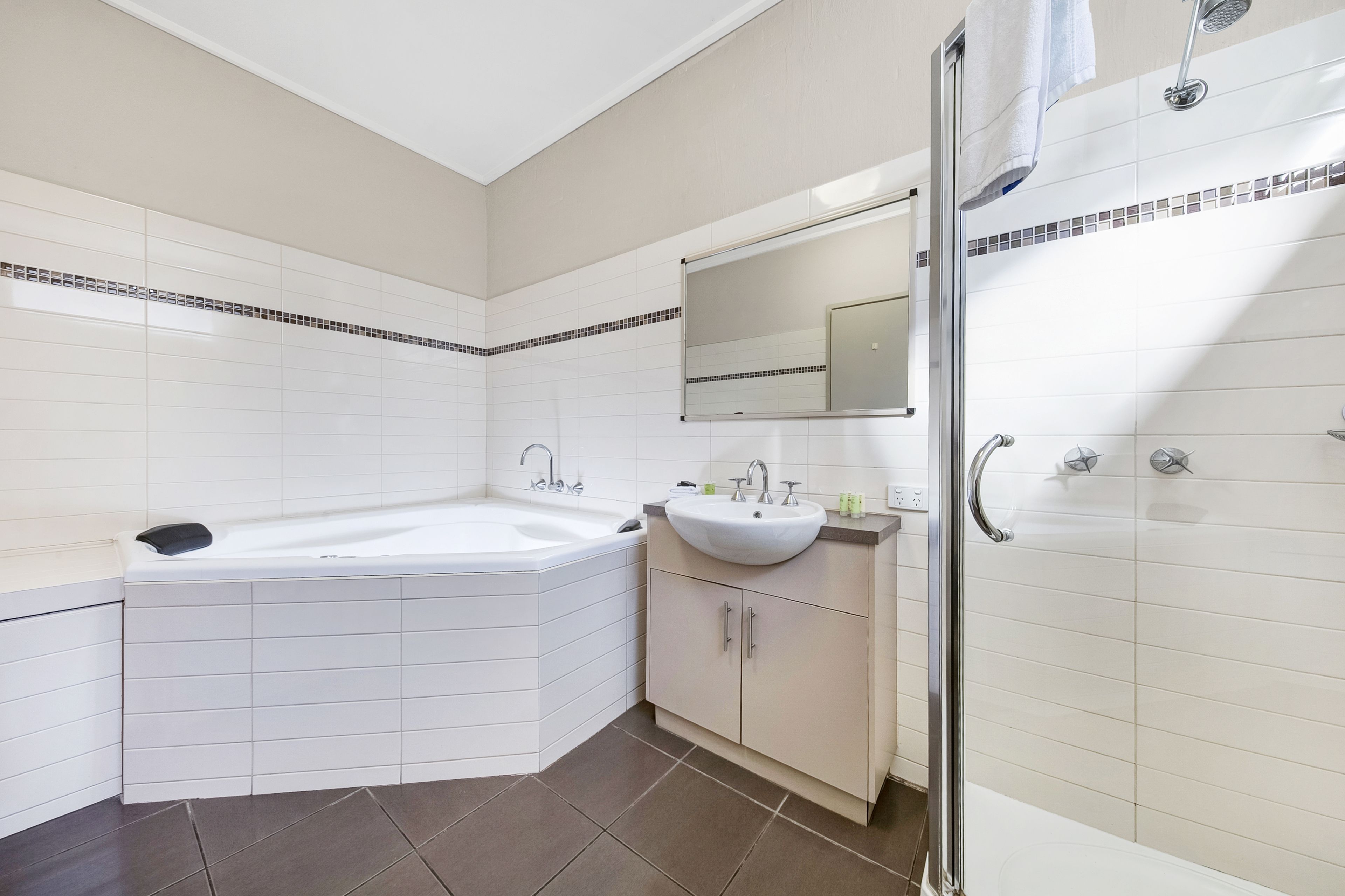 A modern bathroom with a large bathtub, a sink, and a shower area.