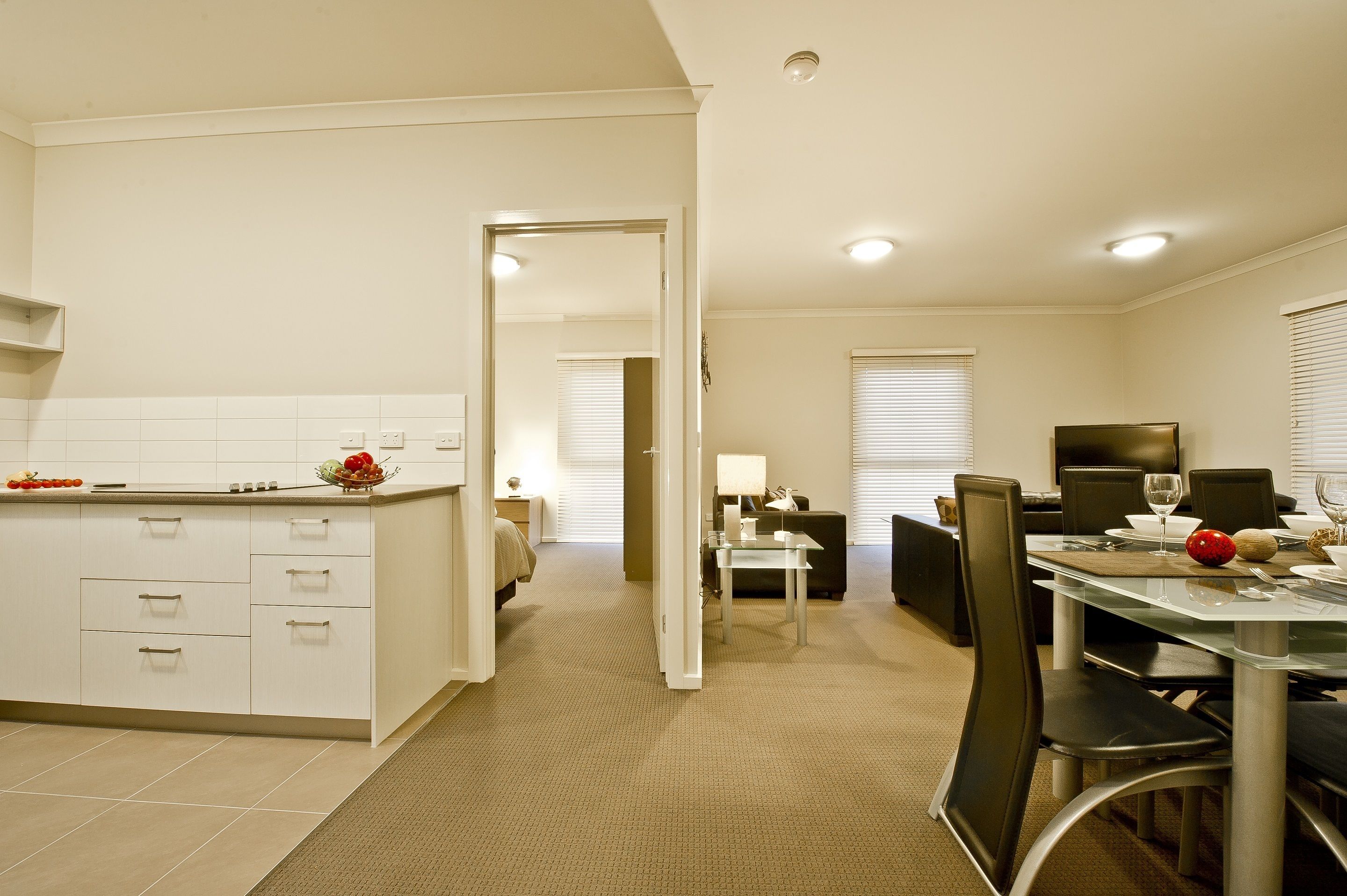 A modern hotel room with a kitchen, dining area, and a separate living space.