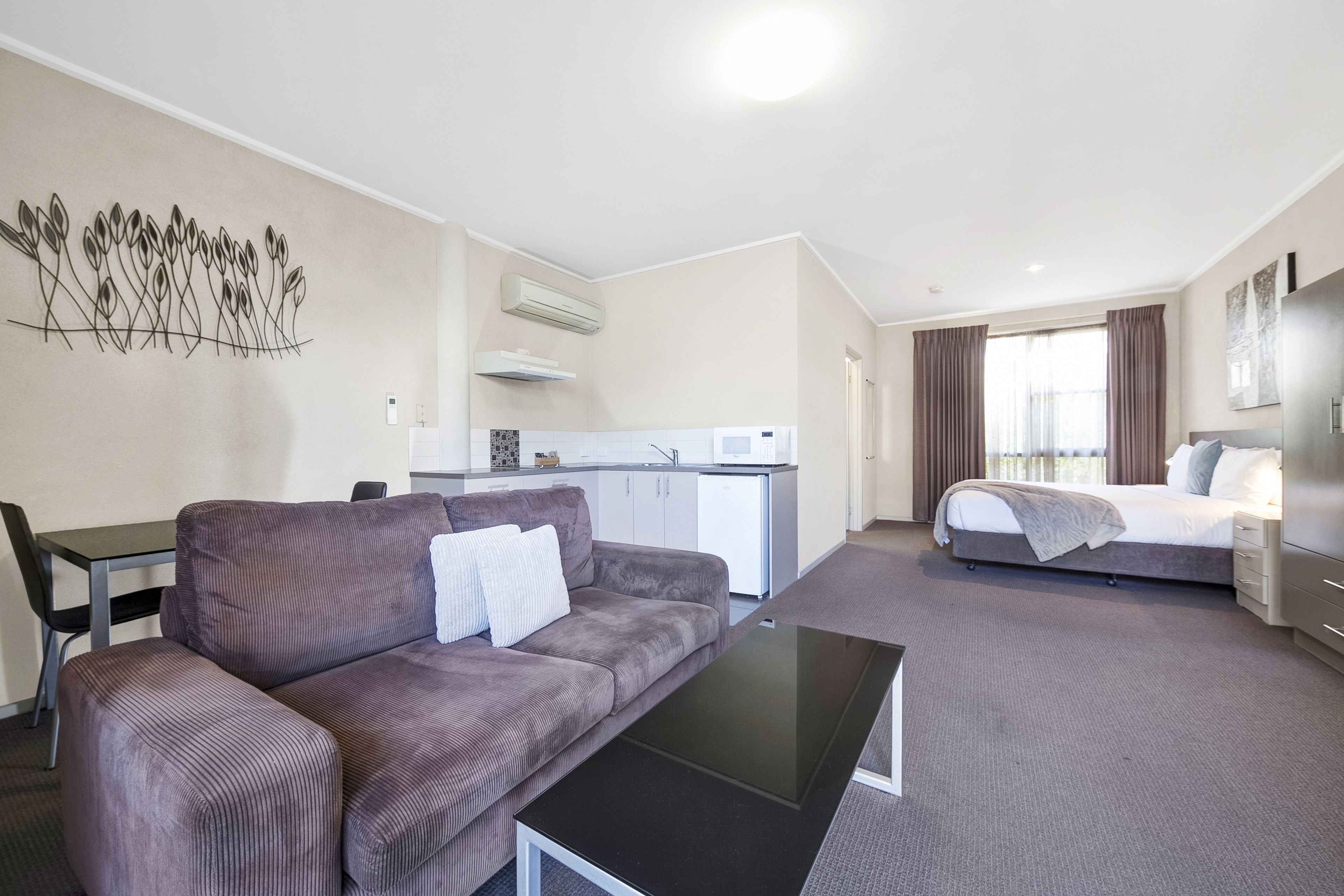 Ein modernes Hotelzimmer mit einer Couch, einem Esstisch, einem Bett und einer Küchenzeile.