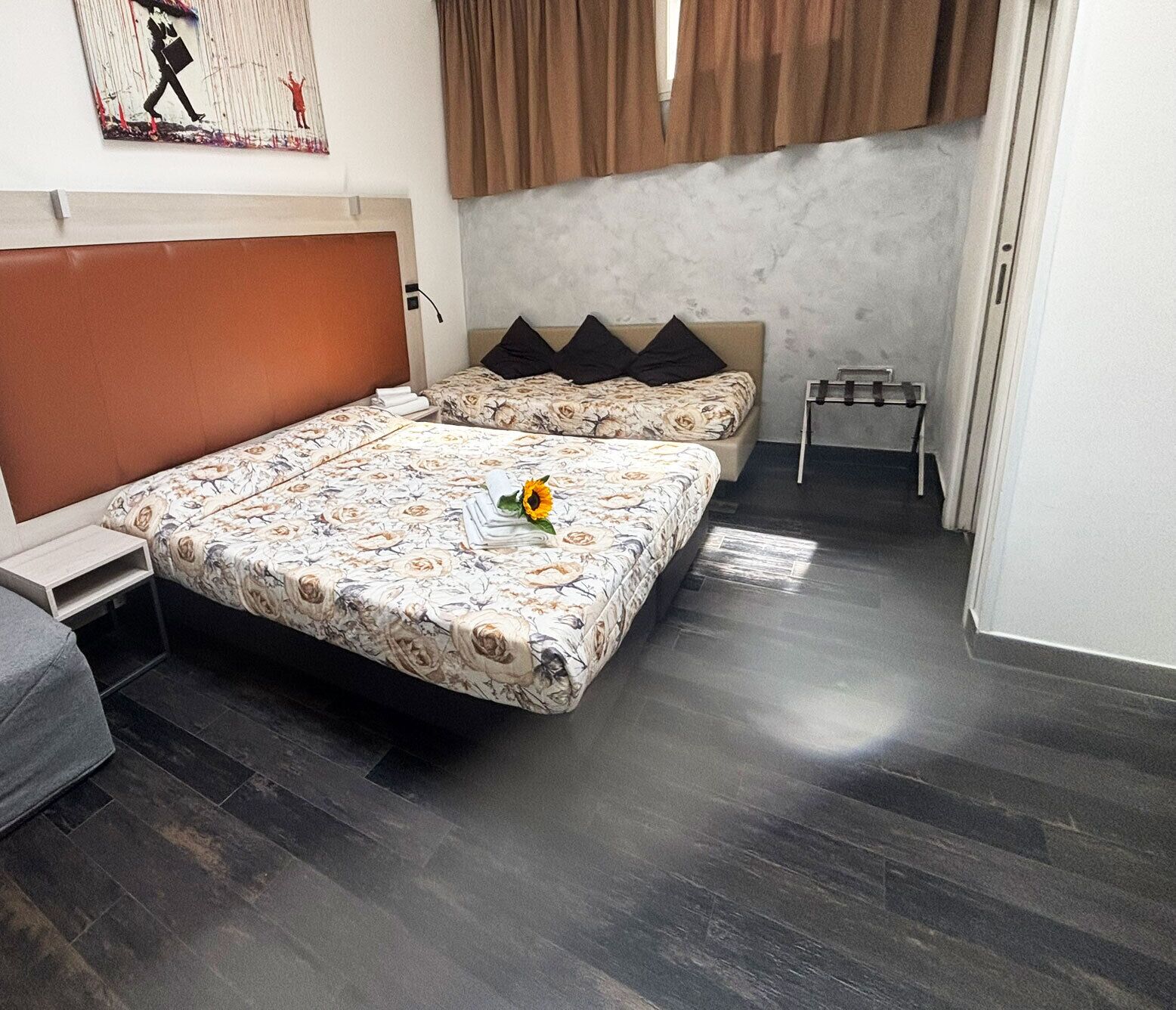 A bedroom with a large bed, a bedside table, a small table, and a wall-mounted artwork.