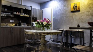 Una cocina moderna con armarios de madera, una mesa de comedor con sillas, un jarrón de flores y un cuadro en la pared.