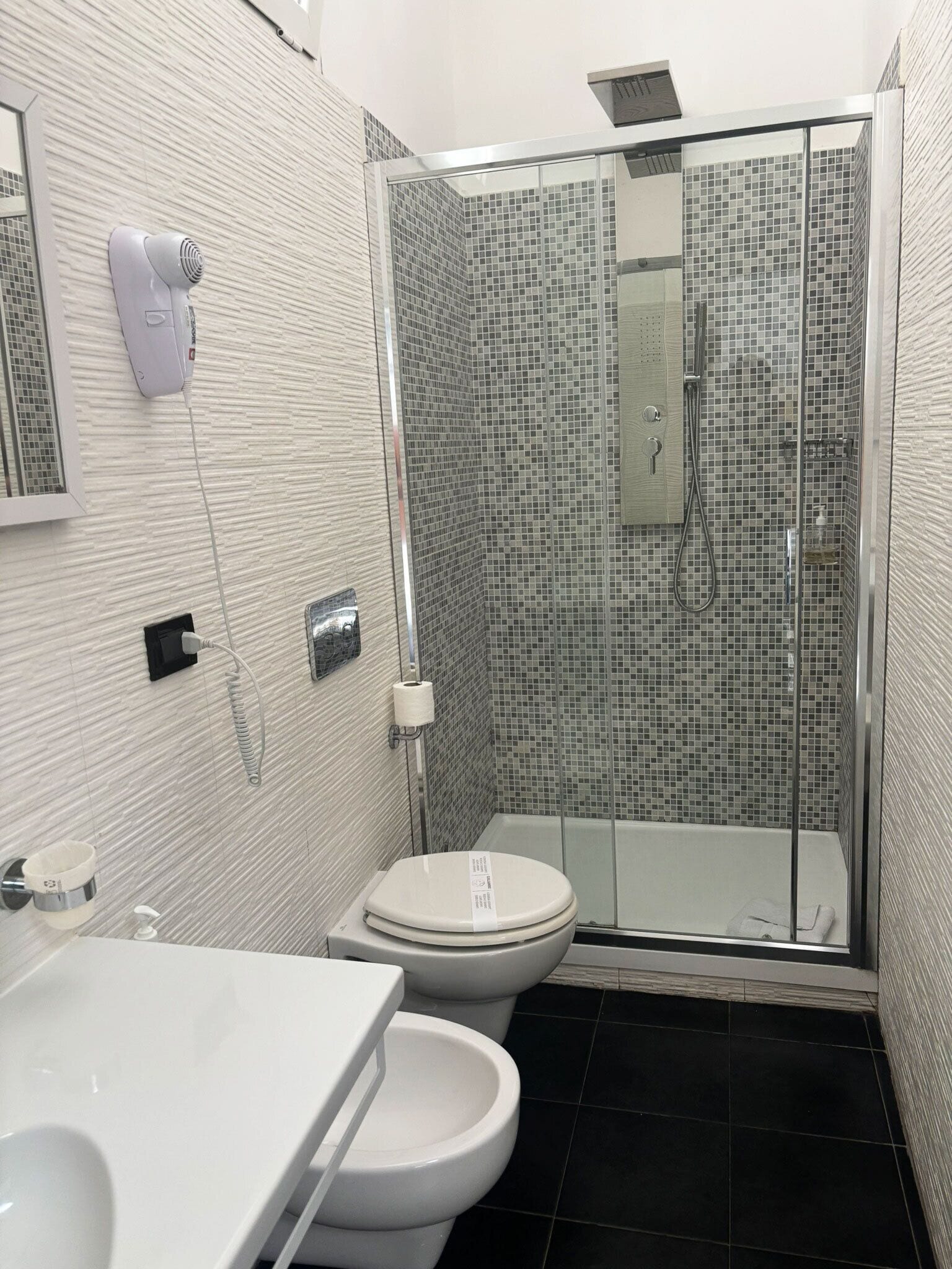 A modern bathroom with a toilet, bidet, and a glass-enclosed shower area.